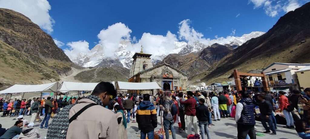 Sacred Kedarnath Temple nestled in the snow-clad Himalayas, surrounded by pilgrims on the Char Dham Yatra trail.