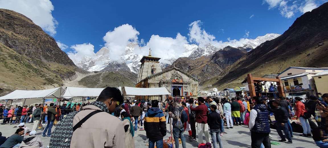 Sacred Kedarnath Temple nestled in the snow-clad Himalayas, surrounded by pilgrims on the Char Dham Yatra trail.